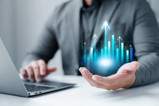 Business growth concept, businessman using laptop, hand holding digital graph and chart and arrow pointing upwards, finance and investment, banking, data analysis and digital transformation.
