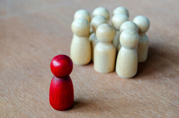 A red figurine facing beige figurines illustrating confrontation that may indicate leadership or harassment.