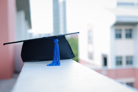 Close-up focus of university graduates placing a bachelor's certificate and a commemorative cap at the graduation ceremony. Success, celebration	