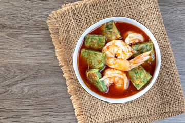 Shrimp Sour Soup with Acacia (Cha-om)  on a wooden table