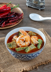 Shrimp Sour Soup with Acacia (Cha-om)  on a wooden table