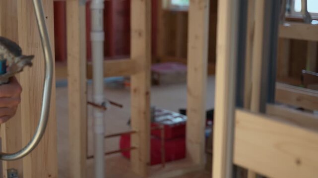 Worker bending a pipe for electrical system installment at home. 