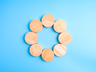 Minimal eco concept with wooden circle blocks arranged in round shape on blue background, symbolizing teamwork, process, infographic template, sustainability, connection, and creative blank space.