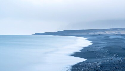 Fototapeta premium Serene Coastal View with Dark Sand Beach and Calm Ocean Waters.