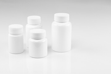 Set of four blank white pill bottles, isolated on white background.