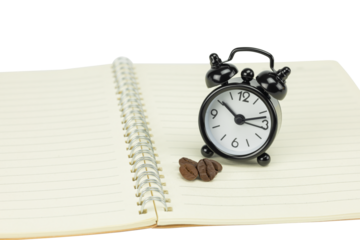 Alarm clock on open notebook with coffee beans, morning coffee concept.
