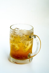 A close-up of a refreshing iced tea in a frosted glass mug. The cold beverage is infused with healthy chia seeds (Salvia hispanica) and ice cubes, shot in a bright, high-key style.