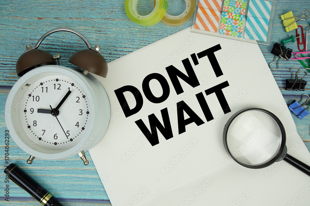 Poster don't wait text written on notepad with alarm clock and magnifying glass flat lay on wooden backgrou
