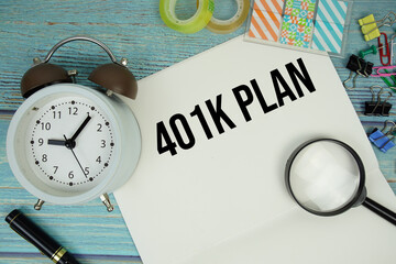 401K Plan text written on notepad with alarm clock and magnifying glass flat lay on wooden background