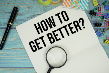 How To Get Better? text on a paper surrounded by office supplies and magnifying glass on a blue...