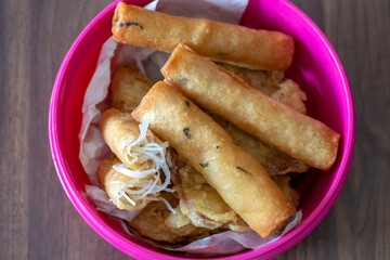  Fried rice vermicelli spring rolls, locally known as risol bihun, served in a bowl. This is a common street food snack sold by vendors.