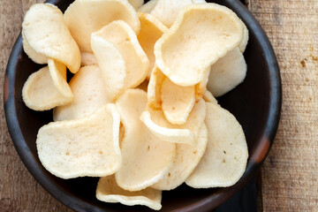 A close-up shot of a pile of white, crunchy prawn crackers, with a rough texture.