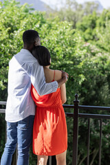 Couple embracing on balcony, enjoying scenic view of lush green landscape