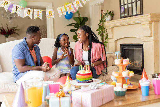Celebrating birthday at home, African American family with cake and gifts, smiling