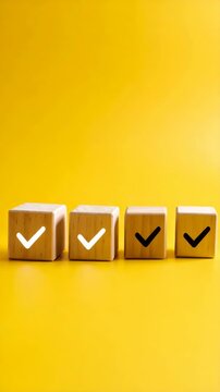 Wooden cubes displaying check mark symbols arranged on a vibrant yellow background representing confirmation and validation.