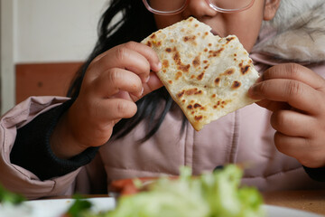 Child enjoying flatbread while seated at a table