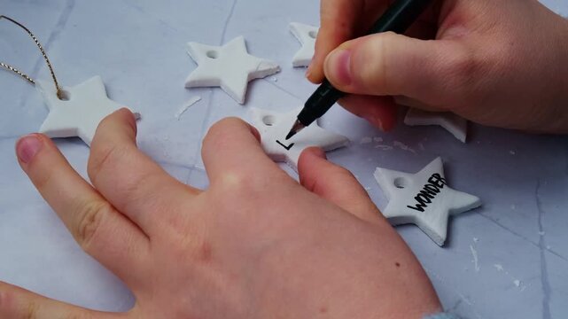Master class writing word LOVE Creator is using white air dry clay for making decor to Christmas tree holiday. Creating hobby recreation activity that involves fingers. DIY crafting Modern art 