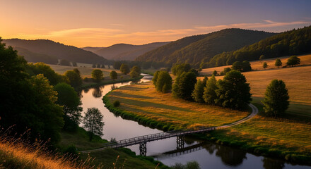 Obraz premium A gentle sweep of golden hour light over a serene river valley, highlighting the winding water and rolling green hills at sunset