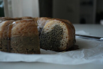Slice of homemade bundt cake with poppy seeds and caramel glaze, rustic autumn dessert on parchment paper, cozy seasonal baking symbolizing warmth and tradition.