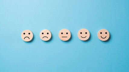 Wooden Level of mental health assessment max positive. cubes blocks with happy and sad face smile face symbol on blue background