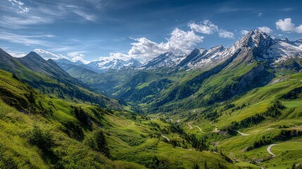 Obraz premium Alpine valley panorama under a vibrant sky. Lush green meadows and winding roads descend into a valley framed by snow-capped peaks