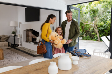Happy family enjoying time together at home, holding teddy bear and smiling