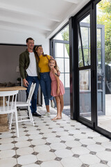 Happy family of three standing together at home, smiling and enjoying moment