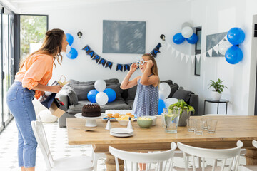 Mother and daughter celebrating birthday at home with cake and decorations