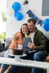 Celebrating birthday, couple hugging and exchanging gift with joy at home