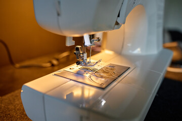 Close-up view of sewing machine needle and presser foot with thread. Concept of sewing and handmade craft