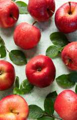 Fresh red apples with green leaves creating appealing pattern on green background