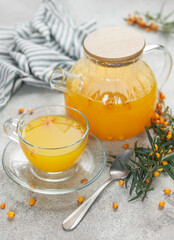 Sea buckthorn tea with fresh berries and a teapot on table