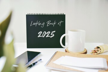 Looking back at 2025 year inscription on desk with office supplies. 2025 highlights, review, evaluation concept.