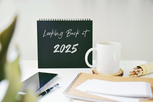 Looking back at 2025 year inscription on desk with office supplies. 2025 highlights, review, evaluation concept.