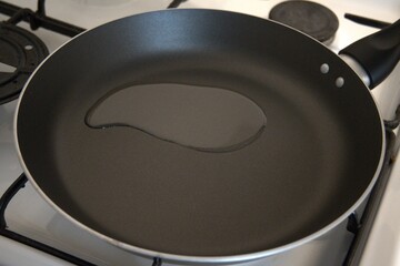 Top view of oil poured into an empty frying pan, ready for cooking.
