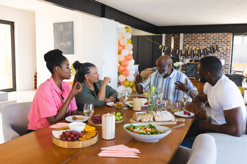 Family enjoying retirement celebration with food and drinks at home, sharing stories