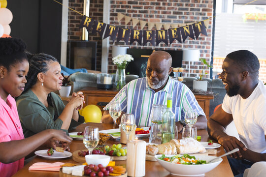 Family celebrating retirement with joyful conversation and delicious meal at home