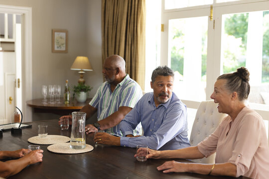 Celebrating togetherness, seniors having drinks and conversation at home, enjoying friendship - Powered by Adobe