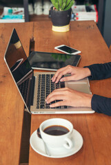 Vertical Horizon Close up businesswoman hand typing laptop drink black coffee cup in green garden cafe. Vertical Woman Hands love drinking hot coffee working from home. Business women typing laptop