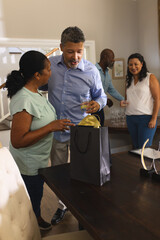 Friends celebrating at home, exchanging gifts and enjoying drinks together