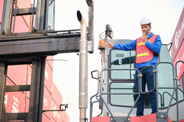 Naklejka premium The worker is using a walkie-talkie to direct the forklift driver to go straight to the container yard