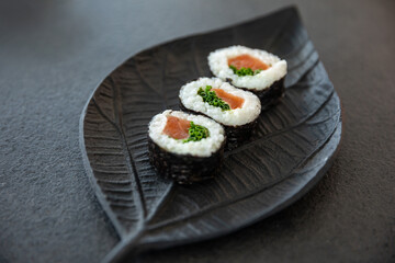 Zestaw sushi na czarnej tacy w kształcie liścia Assorted sushi on a black leaf-shaped tray