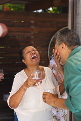 Seniors laughing while drinking at lively outdoor celebration with friends