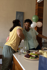 Friends greeting warmly at home, enjoying snacks and drinks on kitchen counter