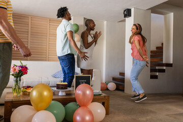 Friends celebrating birthday at home, jumping with joy and excitement
