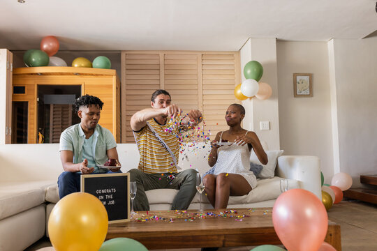 Friends celebrating new job with confetti and cake in living room