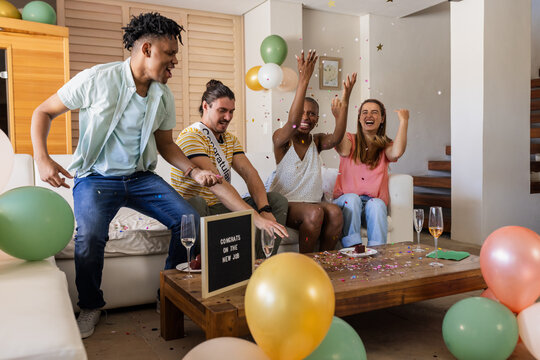 Friends celebrating new job with confetti and balloons in living room
