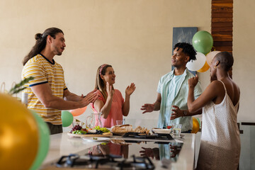 Celebrating at home, friends sharing conversation and laughter around kitchen island