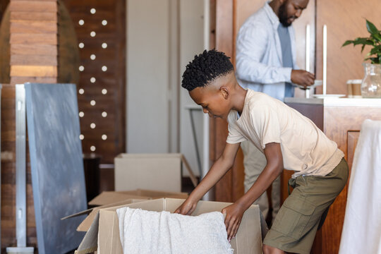 Father and son unpacking boxes in new home, enjoying family time together