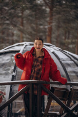 A beautiful woman is relaxing in the forest in winter glamping on the background of a domed tent